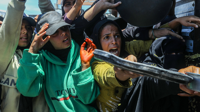 Palestinians receive hot meals distributed by a charity organization in Gaza